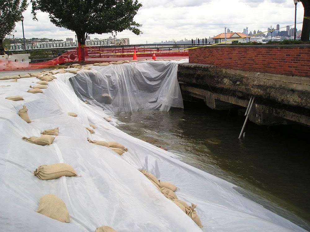 Waterfront wall repair with geotextile and sandbags along the water